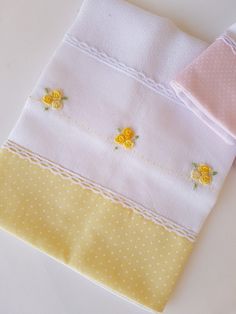 three different colored napkins with yellow flowers and polka dots on white paper, one folded in half