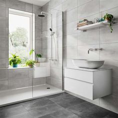 a white sink sitting under a bathroom window next to a shower and bathtub with plants on the ledge