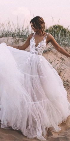 a woman in a wedding dress walking on the beach