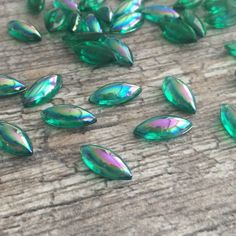 many green glass beads are scattered on a wooden surface, including one with an irregular shape