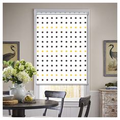 a dining room window with white and yellow polka dots on the roller shades over it