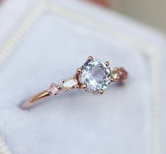 an engagement ring with three stones in it on top of a white napkin and cloth