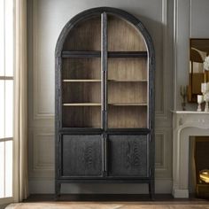 an arched glass door stands in the corner of a room with a fireplace and bookshelf