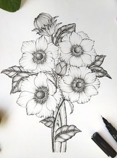 a drawing of some flowers on a sheet of paper with markers and pens next to it