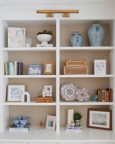 a white book shelf filled with lots of books and vases on top of it