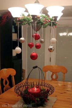 christmas decorations hanging from a chandelier over a dining room table with red and white baubles