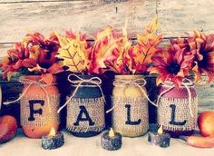 three jars with fall decorations in them sitting on a table