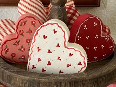 three heart shaped boxes sitting on top of a wooden bowl with red and white hearts