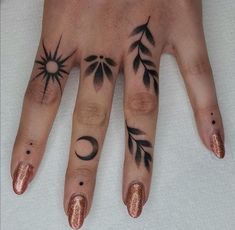 a woman's hand with tattoos on it and two fingers that have sun and moon designs