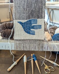 several knitting needles are laying on the table next to an old weaving machine and scissors