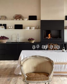 a dining room table with wine glasses on it and a fire place in the background