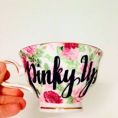 a hand holding a cup with the word pinky fly painted on it's side