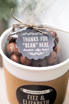 a cup filled with lots of chocolate covered candies next to a sign that says thanks for bean here