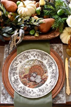 a thanksgiving table setting with pumpkins, gourds and greenery