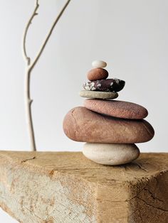 a stack of rocks sitting on top of a wooden block next to a tree branch