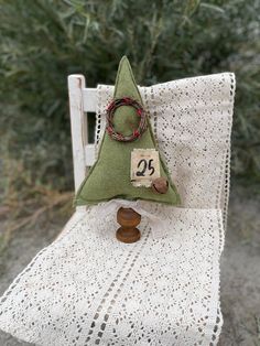 a small green christmas tree sitting on top of a white chair next to a wooden ring