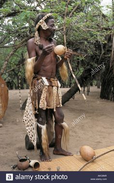 an african man with long hair holding a coconut in his hand and standing next to other items