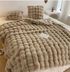 a bed with fluffy blankets and pillows on it