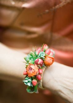 a close up of a person's arm wearing a bracelet with flowers on it