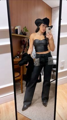 a woman taking a selfie in a mirror wearing black pants and a crop top