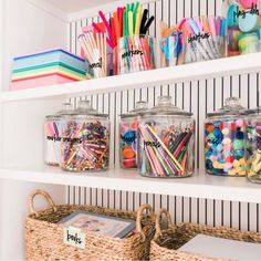 the shelves are filled with different types of pens and pencils in glass jars on top of wicker baskets