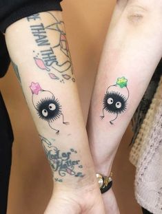 two people holding hands with tattoos on their arms and one has an eyeball in the middle