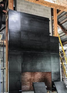 a man standing on top of a black piece of wood in a room under construction