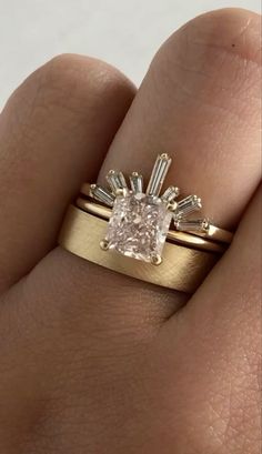 a woman's hand with a gold ring and a pink diamond in the middle