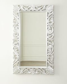 an ornate white mirror hanging on the wall