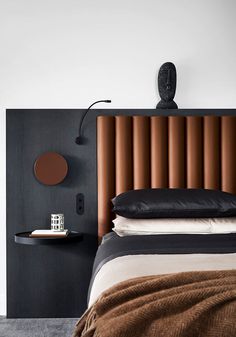 a bed with black headboard and white sheets in a modern bedroom, next to a wall mounted clock