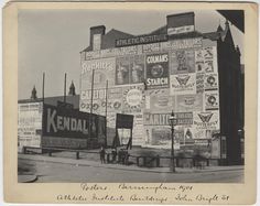 an old black and white photo of a building with many advertisements on the side of it