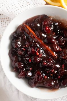 a white bowl filled with cranberry sauce next to an orange slice