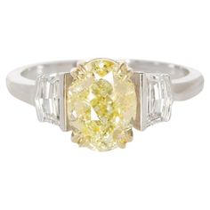 This ring, presented by Antinori di Sanpietro, showcases a radiant 2.00 carat oval brilliant diamond with a fancy yellow color and VS1 clarity, as certified by GIA. The diamond's hue is vibrant, and its cut allows for a striking dispersion of light, creating an enchanting sparkle. This central stone is gracefully complemented by the use of both 18k white and yellow gold in the band, harmonizing the diamond's warmth with the cool luster of the metal. Epaulette diamonds are set on either side of t Fancy Yellow Diamond, Fine Jewels, Three Stone Rings, Yellow Gold Ring, Yellow Diamond, Brilliant Diamond, 2 Carat, Oval Diamond, Jewelry Rings Engagement