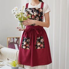 a woman wearing an apron holding flowers in her hand