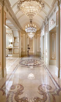 an elegant hallway with chandelier and marble flooring is pictured in this image