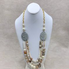 "An artistic collaboration of classic pearls and Tibetan agate and natural unpolished agate stones with geode crystallization peaking through like little hidden gems in this neutral toned long bib necklace. This 3-strand bib hangs from metal calla lily stampings that have been given a chic soft white and golden aged patina. Stunning gold-plated cable chain in a longer length adds the finishing touch for a dramatic bold look. Pearls are classic, timeless and never go out of style. 30\"L. Lobster Multi-strand Pearl Necklace With Natural Stones, Multi-strand Mother Of Pearl Beaded Necklaces, Elegant Long Agate Necklace, Magnolia Collection, Bib Necklace, Calla Lily, Agate Stone, Soft White, Hidden Gems