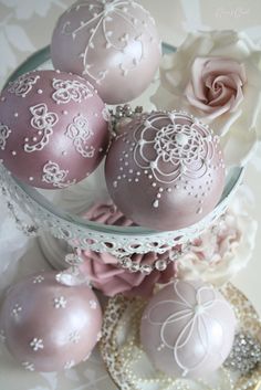 some pink and white ornaments in a glass bowl on a lace doily table cloth