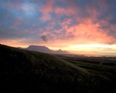 the sun is setting on top of a hill