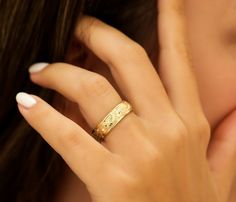 a close up of a person wearing a ring on their finger and holding it to her face