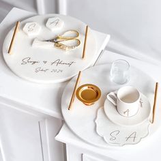 two personalized wedding cake plates with gold scissors and rings on them, sitting next to each other