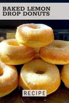 a pile of baked lemon drop donuts sitting on top of each other in front of a sign