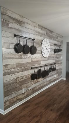 a kitchen wall with pots and pans mounted to it's sides, along with hanging utensils