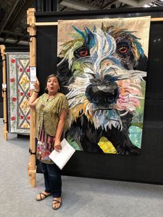 a woman standing in front of a painting holding a piece of paper next to it