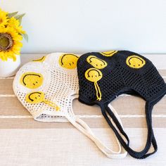 two crocheted hats sitting on top of a table next to a sunflower