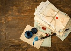 some old envelopes and an ink pen on a wooden table