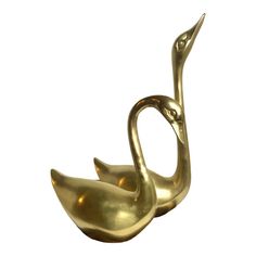 two brass swan figurines sitting side by side on a white background, one is facing the other