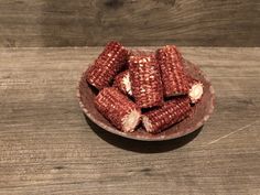 a bowl filled with cooked corn on top of a wooden table