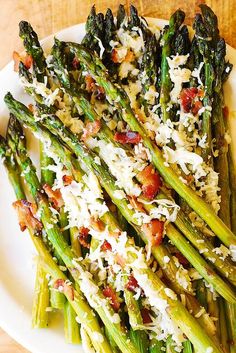 grilled asparagus with bacon and parmesan cheese on a white plate