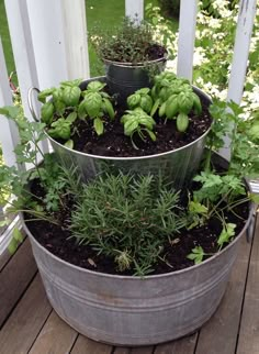 two metal buckets filled with plants on top of a wooden deck