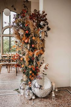 an arrangement of flowers and disco balls on the floor in front of a large window